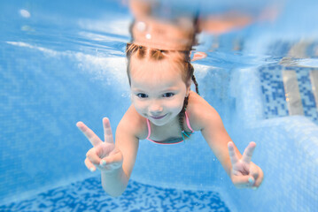 Little girl swims under water in paddling pool. Diving. Learning child to swim. Enjoy swimming and...