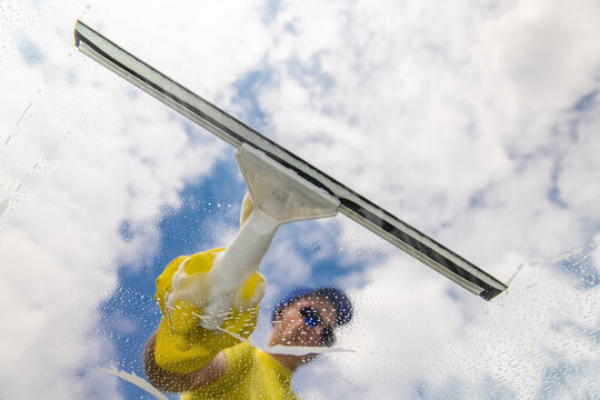 window cleaner cleaning window with squeegee and wipe