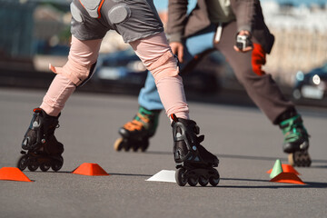 The child is rollerblading in the city. Father filming his daughter on roller skates.