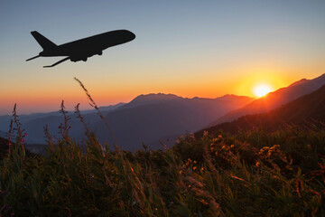 Fototapeta na wymiar travel agency, trips, cheap air travel, plane ticket booking,air transportation, silhouette of an airplane taking off at sunset on sky background over mountain landscape