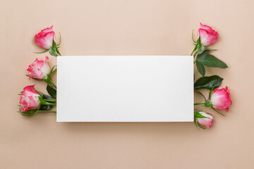 Invitation or greeting card mockup with blank paper and pink rose on a beige background.