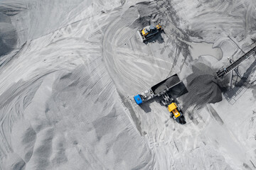 Industrial excavator dump stone, crushed stone or sand truck loading process. Aerial top view