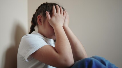 sad girl sitting in the corner crying a covered her face with her hands. family violence abuse child concept. parents punished the child put in a corner. indoor child in depression crying lifestyle