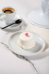 Fresh dessert on a white plate among white dishes with tea and coffee in a cafe