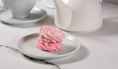 Fresh dessert on a white plate among white dishes with tea and coffee in a cafe