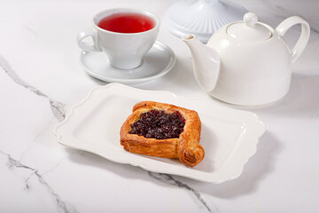 Fresh dessert on a white plate among white dishes with tea and coffee in a cafe