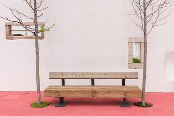 Wooden bench with bare trees against a white wall at the Almonda park, Torres Novas, Portugal