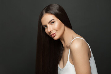 Portrait of beautiful young woman with healthy long hair on black background