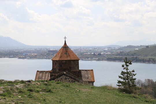 The temple of the ancient Sevanavank monastery on Lake Sevan in Armenia and fragments of the destroyed monastery wall. Holy historical sites in Amenia.