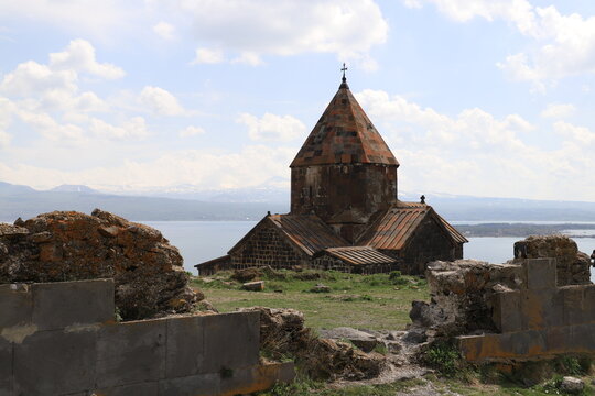 The temple of the ancient Sevanavank monastery on Lake Sevan in Armenia and fragments of the destroyed monastery wall. Holy historical sites in Amenia.