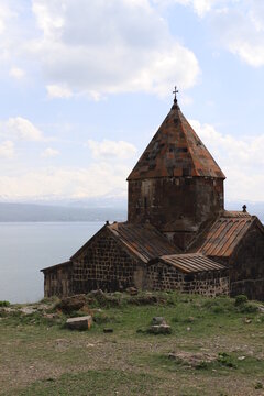 The temple of the ancient Sevanavank monastery on Lake Sevan in Armenia and fragments of the destroyed monastery wall. Holy historical sites in Amenia.