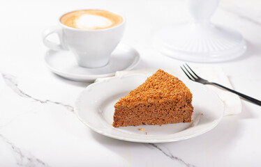 Fresh dessert on a white plate among white dishes with tea and coffee in a cafe