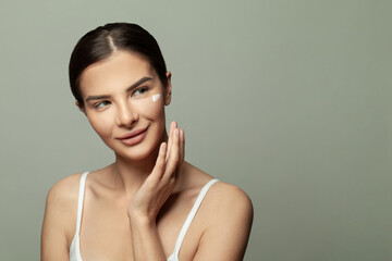 Closeup head shot pleasant beautiful woman applying moisturizing creme on face after shower. Smiling young pretty lady, daily morning routine concept.