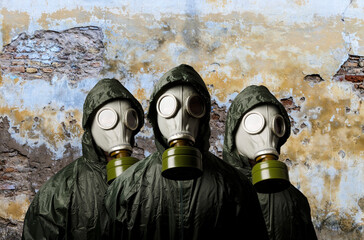 Gas masks. Three people with gas masks and brick wall behind with copy space.