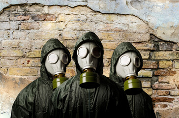 Gas masks. Three people with gas masks and brick wall behind with copy space.