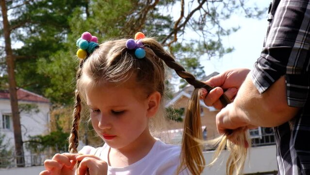 Grandmother pigtails braiding granddaughter's hair outdoors