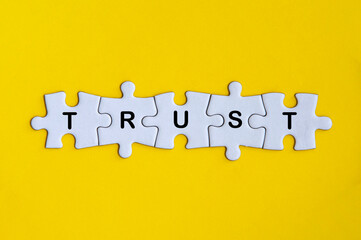 Word trust missing jigsaw puzzle on yellow cover background.