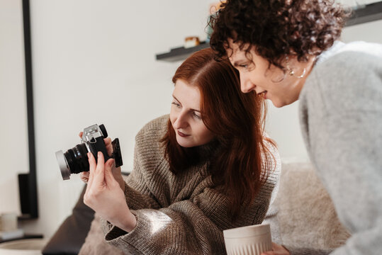 Vertical shot of a redhead female showing a photo to a curly woman