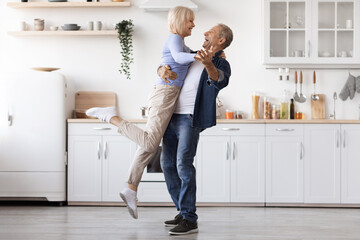 Romantic elderly man and woman dancing at kitchen