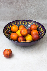  blood oranges on a colorful dish on a gray background.