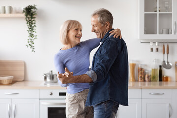 Loving senior couple enjoying time together in kitchen, dancing