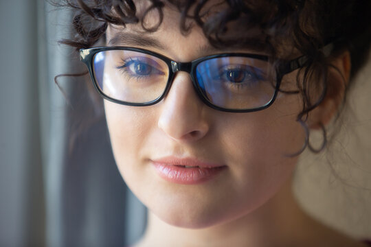 Portrait of beautiful Ukrainian woman in nerd glasses. Cute young female with curly hair