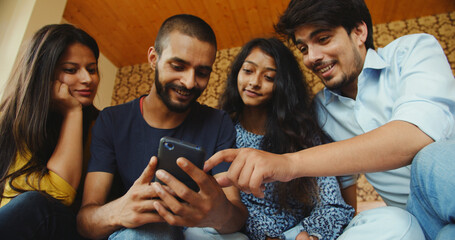Group of oung Indian people happily talking and looking at the phone