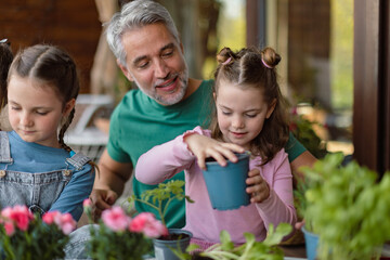 Little daughters helping father to plant flowers, home gardening concept