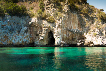 Cave in a cliff with trees on the water