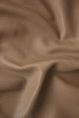  a piece of caramel beige artificial leather close-up with Abstract waves and folds of fabric