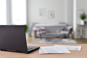 Table with laptop in home office interior.