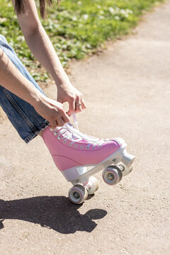 legs of a woman tying pink roller skates