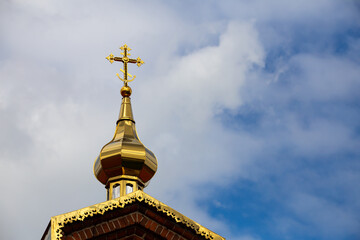 Fototapeta na wymiar Orthodox cross on top of the church against the cloudy sky. Photo taken in natural light of cloudy day