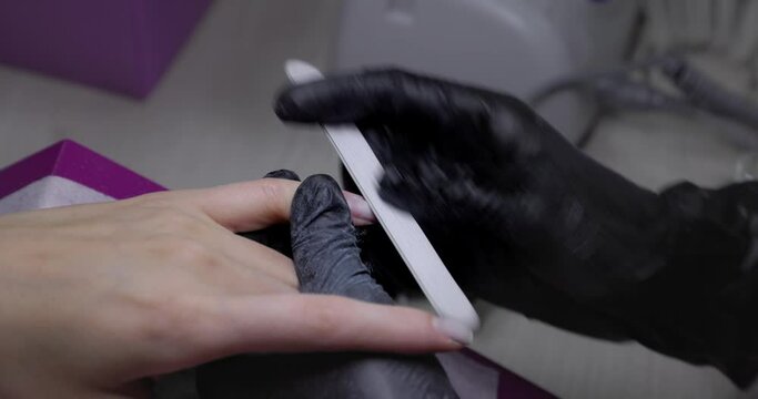 Nail polishing nail file. Close-up women polishing his hand's nails with nail file. The manicure master grinds the nails with a nail file 