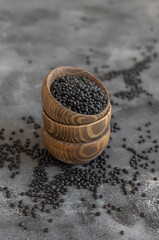Fototapeta na wymiar Wooden bowls of dry black lentils beans on grey table close up, protein source for vegetarian diet