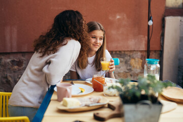 mother kiss her daughter while having breakfast