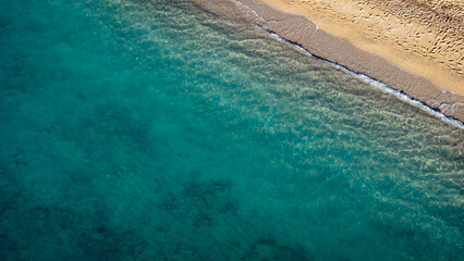Fototapeta na wymiar Aerial view of beautiful sandy beach with footprints and soft turquoise ocean wave. Tropical sea in summer season on Kathisma beach on Lefkada island.