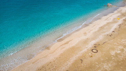 Aerial view of beautiful sandy beach and soft turquoise ocean wave. Tropical sea in summer season on Megali Petra beach on Lefkada island.