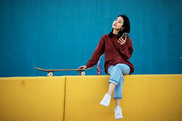 Beautiful Chinese woman with skateboard. Portrait of urban young girl outdoors. © Jelena