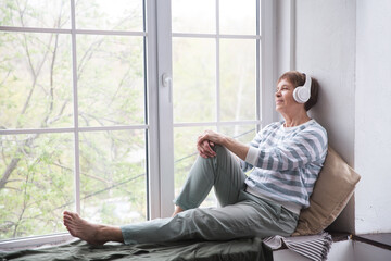  Audio healing. concept without stress. senior woman in headphones listens to music at home. 