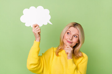 Photo of pensive interested aged lady hold paper speech cloud ponder isolated green color background