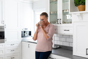 Senior caucasian woman drinking coffee in kitchen at home
