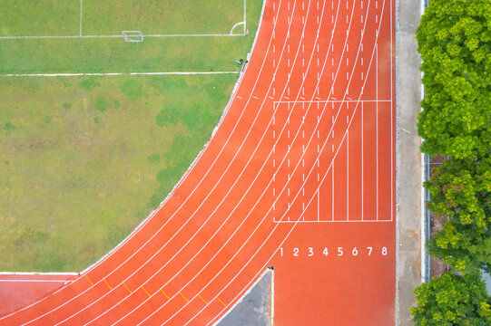 Aerial top view of rubber floor, red running track on a sports stadium with grandstand. Sport and recreation background.