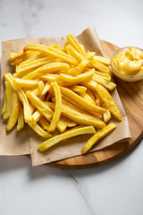 Food concept yellow potato french fries on platter and cheese sauce close up