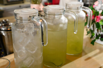 Three decanters with soft drinks or fruit juices on a wooden table