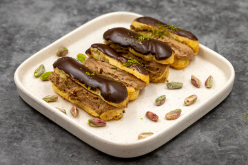 Chocolate eclair cake. Pistachio and chocolate eclair cake on a dark background. close up