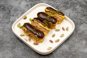 Chocolate eclair cake. Pistachio and chocolate eclair cake on a dark background. close up