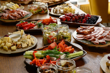 A table with various snacks, fruits, vegetables, cheeses, sausages.
