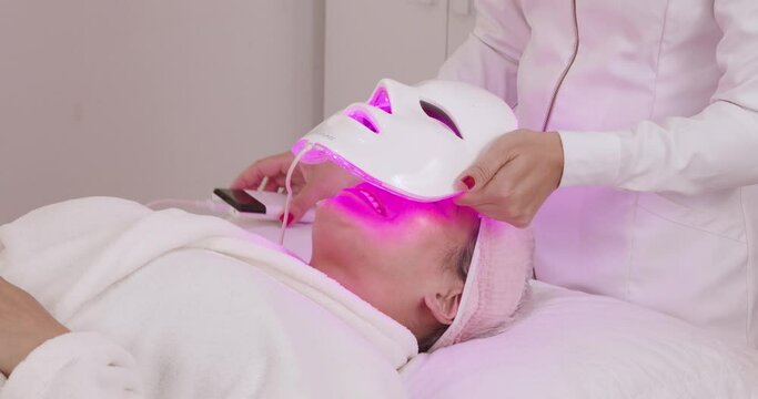 Use of led mask on patient for aesthetic treatment, relaxation, rejuvenation, color therapy, light therapy, skin care. close on procedure