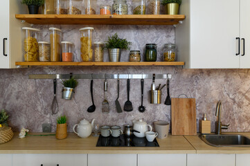 A variety of pasta in containers-cans with bulk products are on the shelves in the kitchen